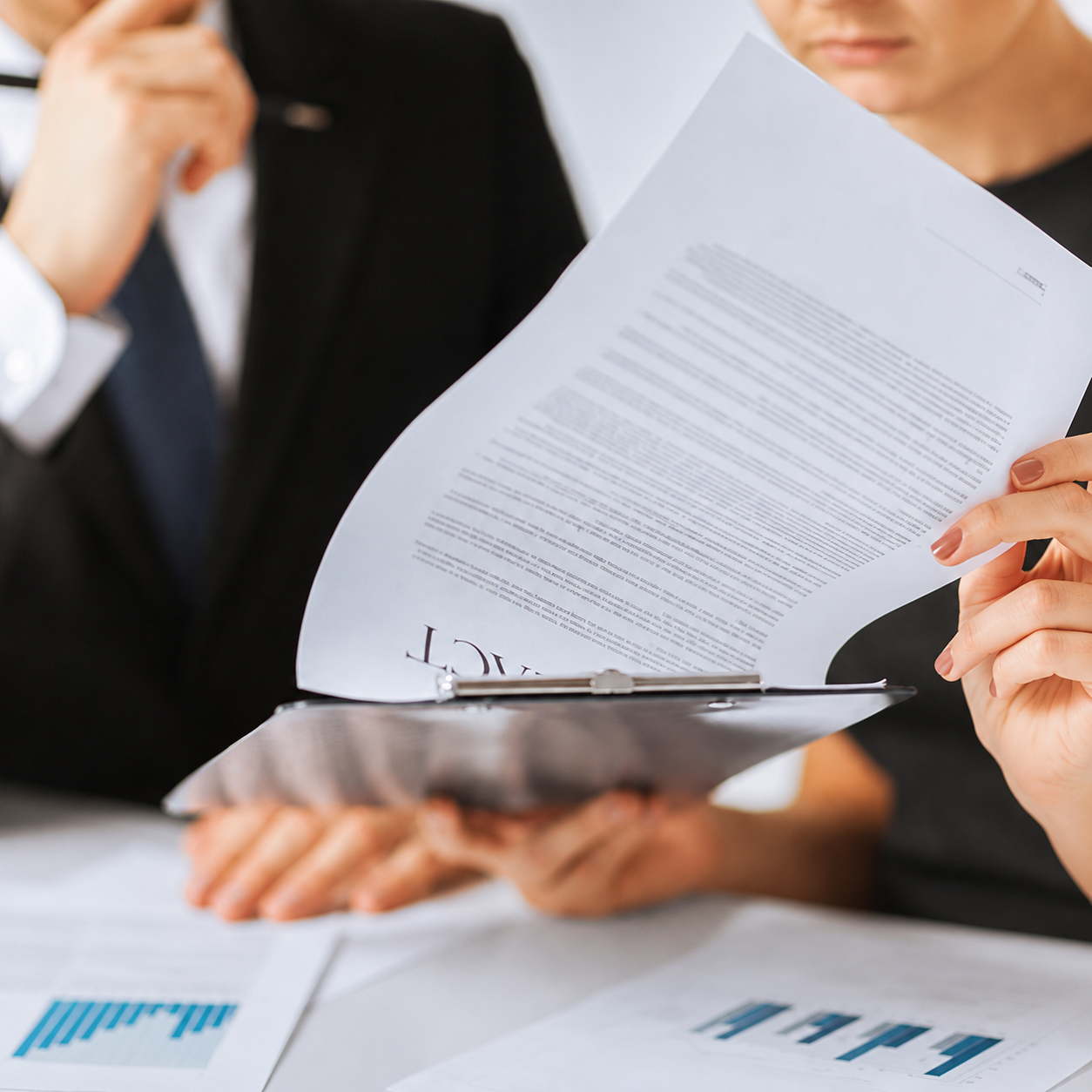 Three people in business attire review documents with charts and text, focusing on a contract or legal document in a binder with a probate attorney.